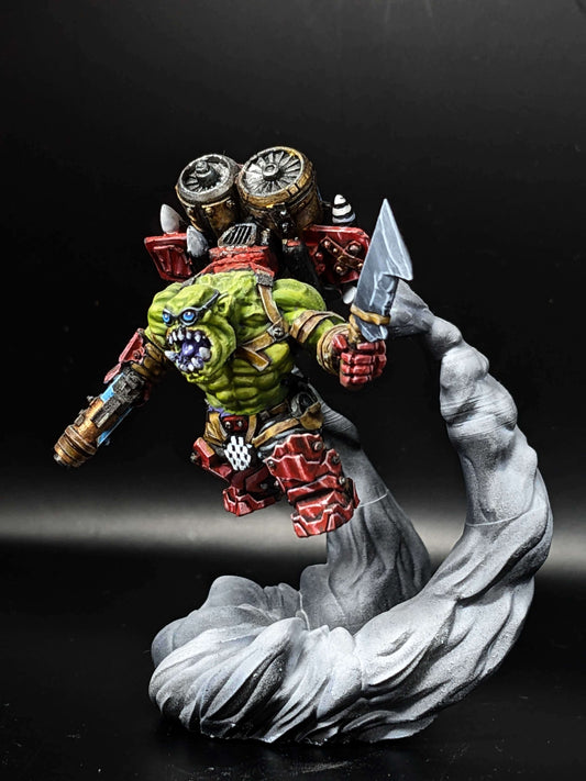 Vibrant green Ork model with jetpack and weapon, captured mid-action on a dramatic swirling cloud base.