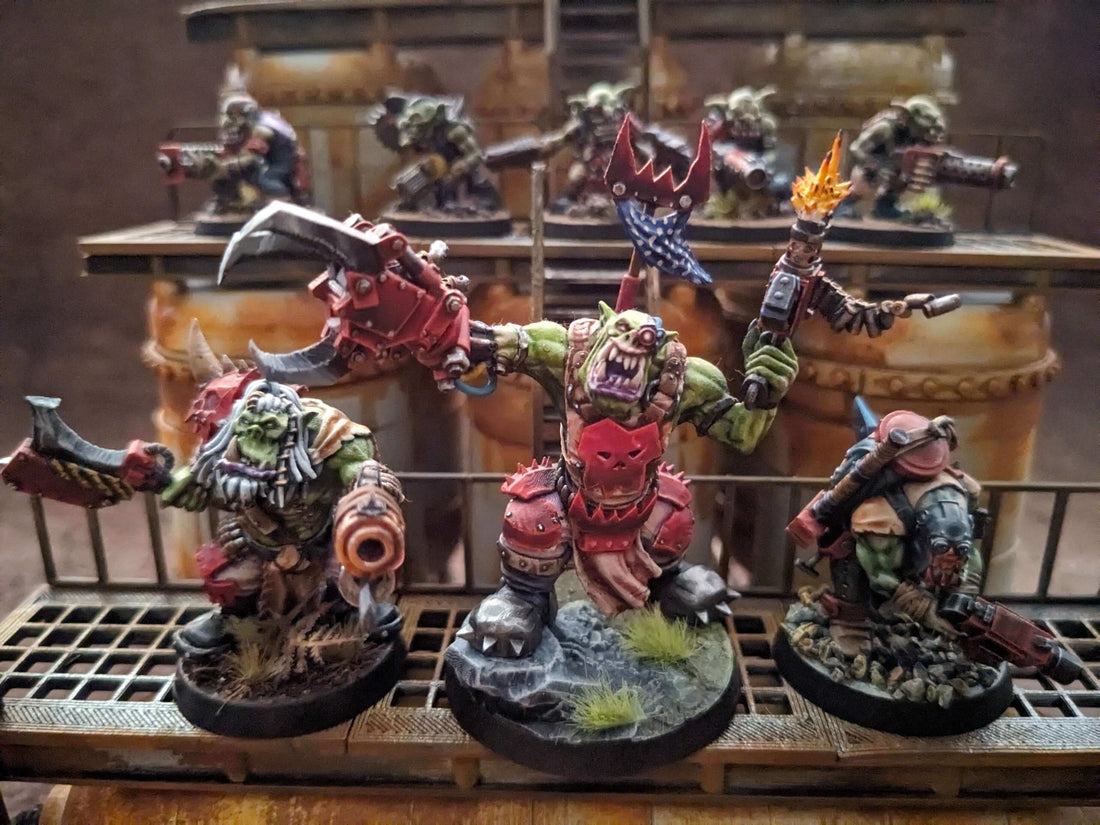 Highlighted miniature orc models for tabletop wargaming on a scenic terrain backdrop.