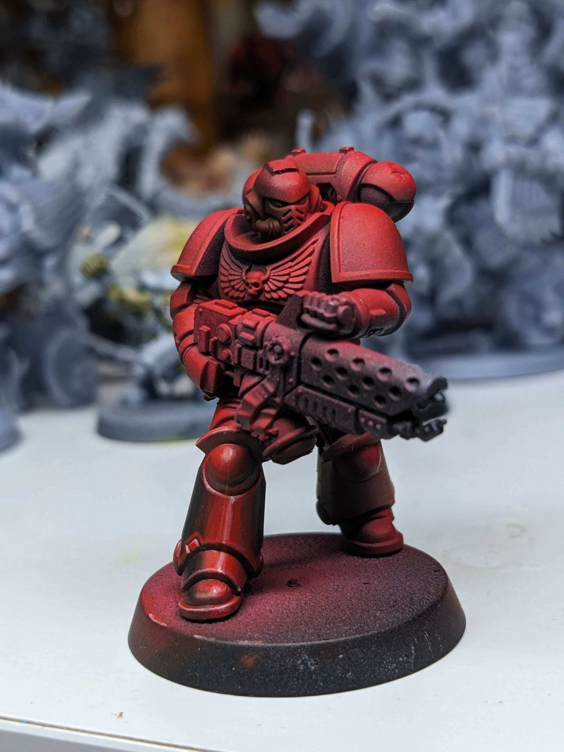 A red-painted miniature soldier holding a weapon, showcasing details of armor and design on a display base.