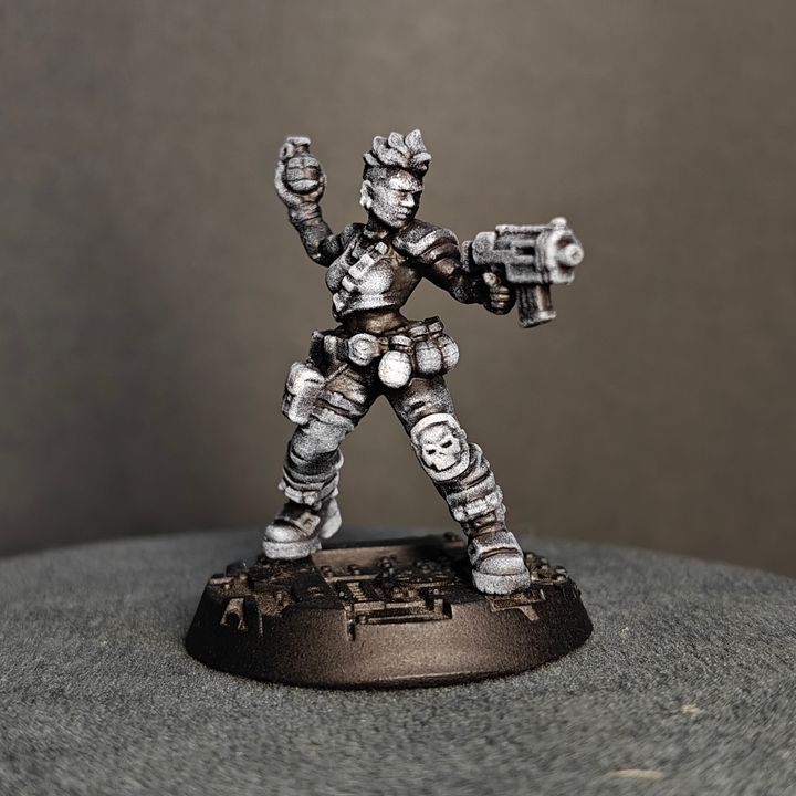 Female grenadier miniature with skull kneepads, pistol aimed and grenade raised, three-quarter front view